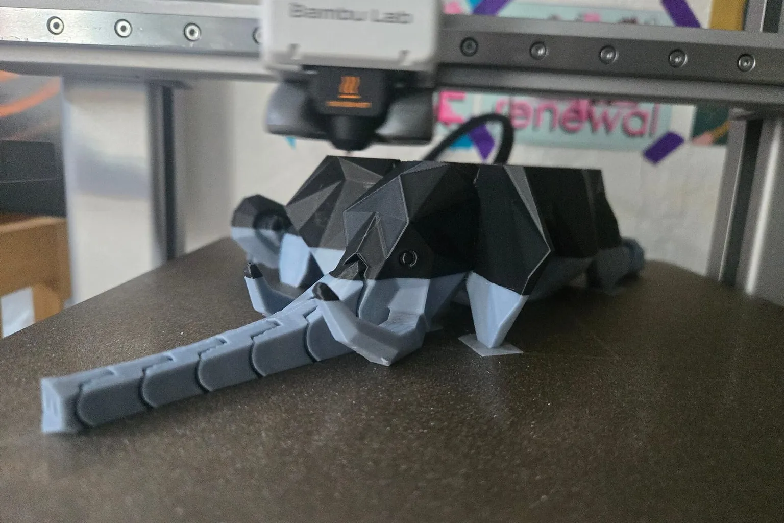 A Bambu Lab printer finishing a two-color articulated elephant