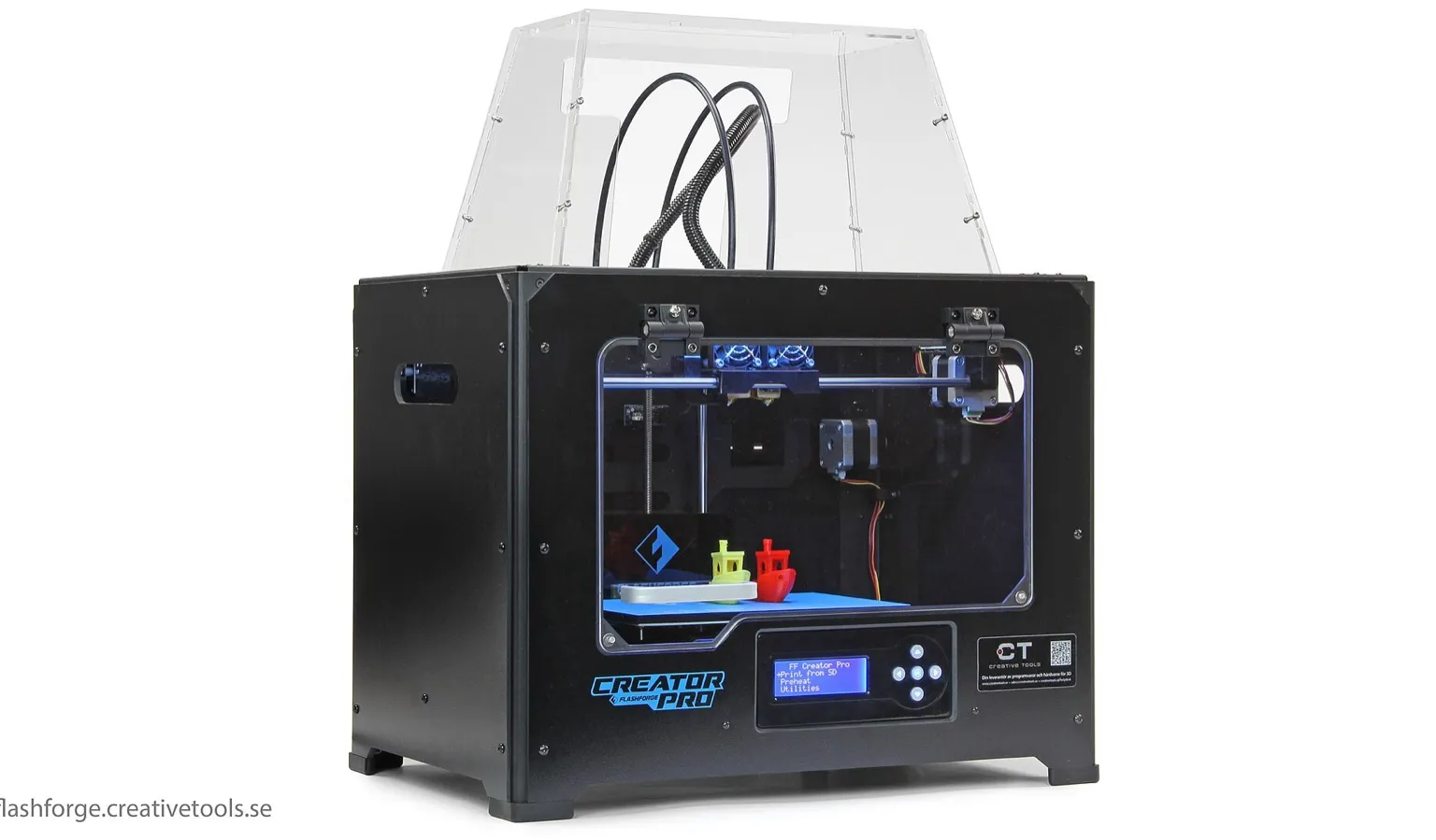 A black Flashforge Creator Pro desktop 3D printer with a clear acrylic lid and two print heads, with a yellow and a red 3DBenchy boat on the blue build plate