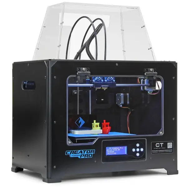 A black Flashforge Creator Pro desktop 3D printer with a clear acrylic lid and two print heads, with a yellow and a red 3DBenchy boat on the blue build plate