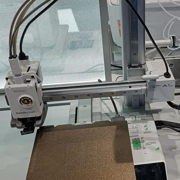 A Bambu Lab A1 mini on a store display: the toolhead with filament tubes plugged in on the X gantry, a textured PEI plate on the bed, the touchscreen and the A1 mini label on the Z column