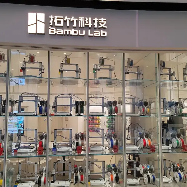 Rows of Bambu Lab printers running behind the glass front of a Bambu Lab store