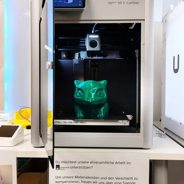 A Bambu Lab X1 Carbon with its door open and a finished green print on the bed