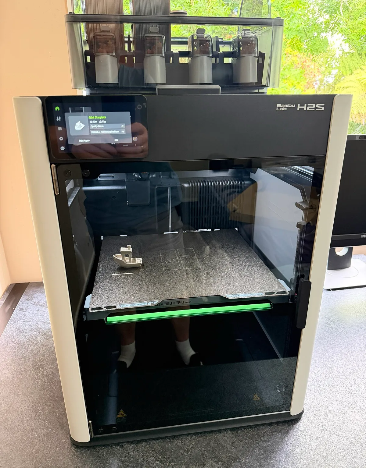 A Bambu Lab H2S printer with an AMS unit on top and a printed boat on its build plate