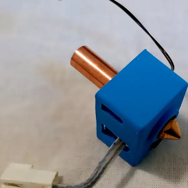 A V6-style hotend with a copper heat break, a silicone sock on the heater block and a brass nozzle