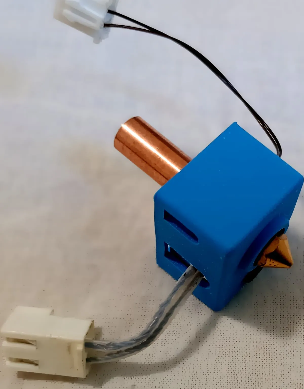 A V6-style hotend with a copper heat break, a silicone sock on the heater block and a brass nozzle
