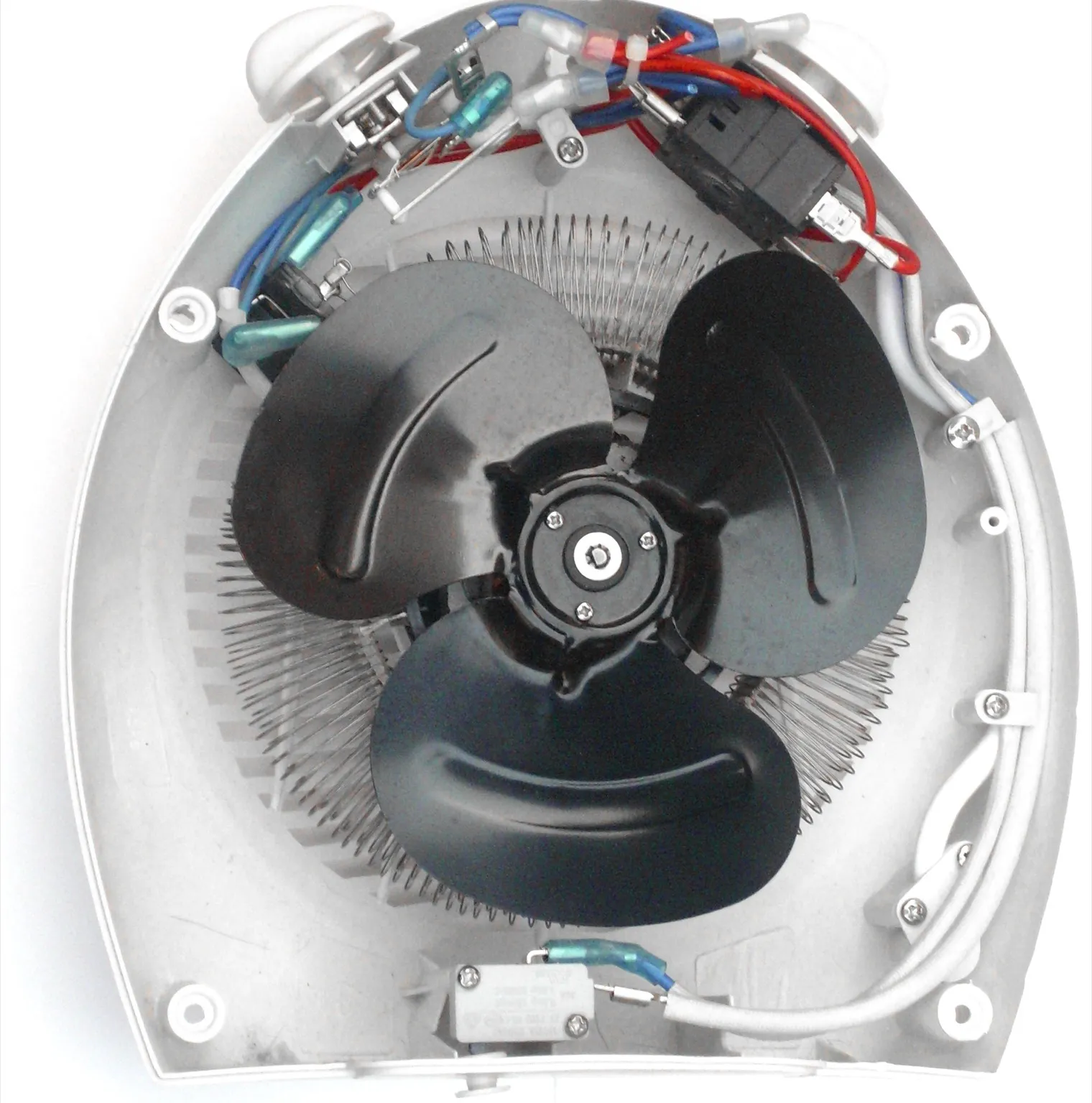 The inside of an opened electric fan heater: a black three-blade fan in front of a coiled heating element, crimped wiring and switches along the top, and the power cable held by clamps down one side
