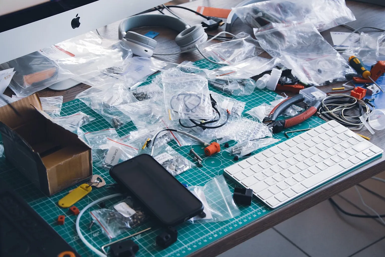 A workbench covered in bagged printer parts, wiring and tools during a printer build
