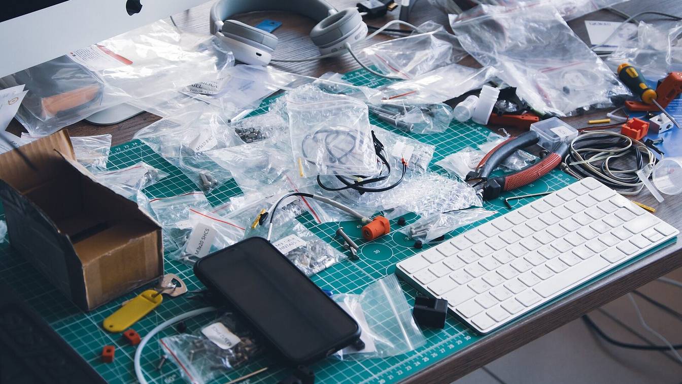 A workbench covered in bagged printer parts, wiring and tools during a printer build