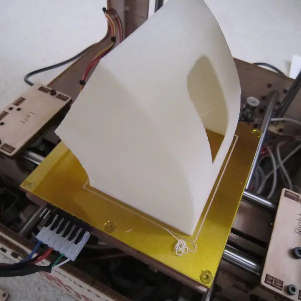 A finished white print being lifted off a printer's heated bed