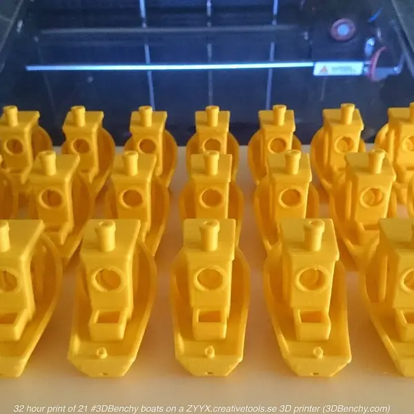 Twenty-one yellow 3DBenchy boats printed together on one build plate