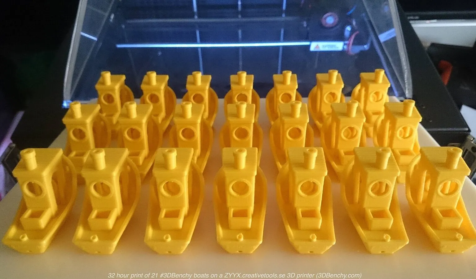 Twenty-one yellow 3DBenchy boats printed together on one build plate