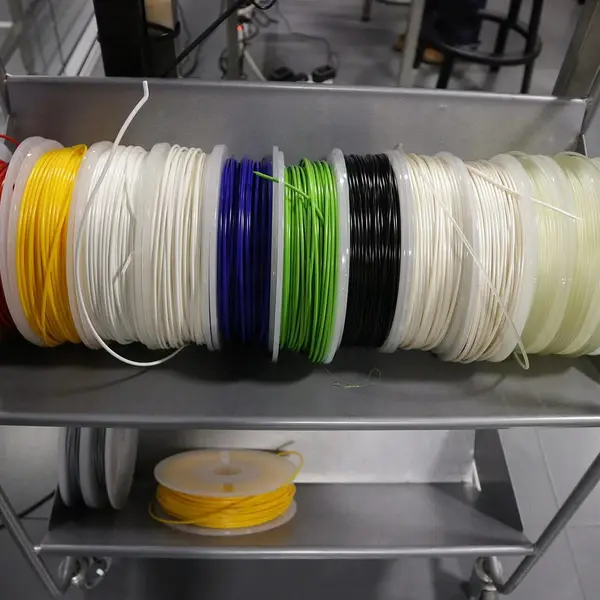 A cart holding a row of filament spools in red, yellow, white, blue, green and black