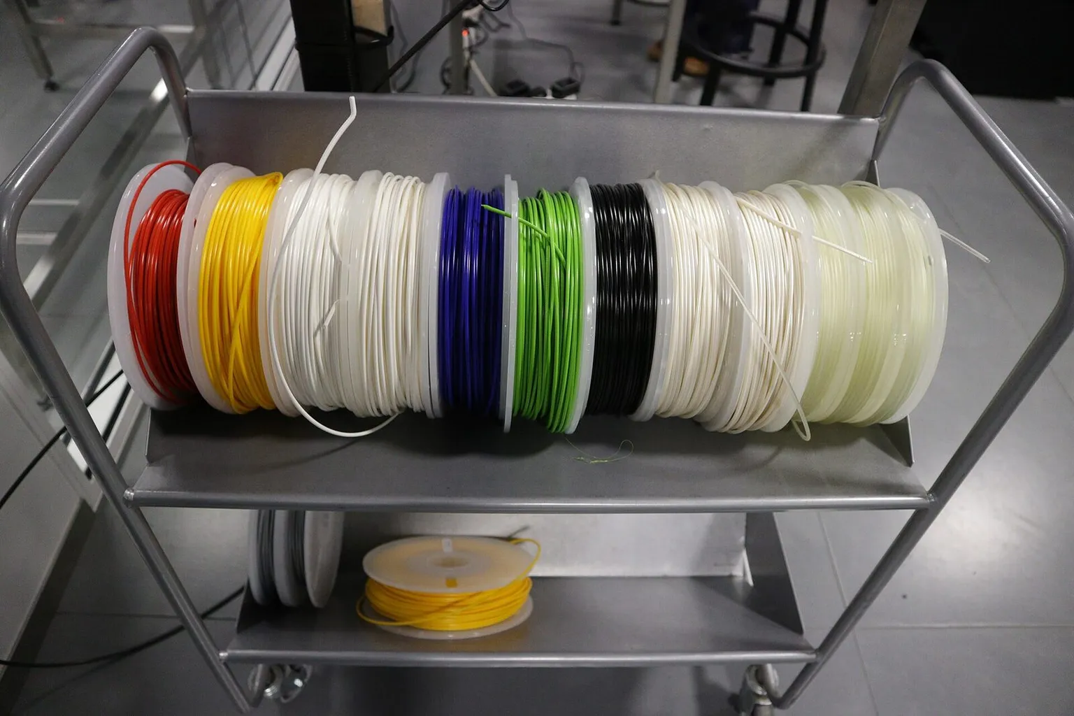 A cart holding a row of filament spools in red, yellow, white, blue, green and black