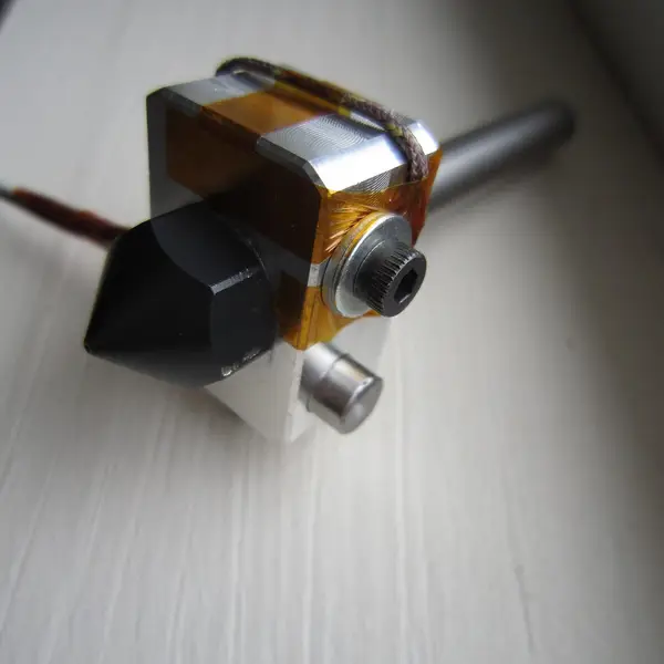 A hot end heater block with a temperature sensor held in place by Kapton tape