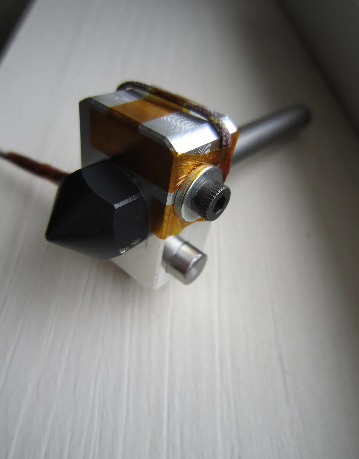 A hot end heater block with a temperature sensor held in place by Kapton tape