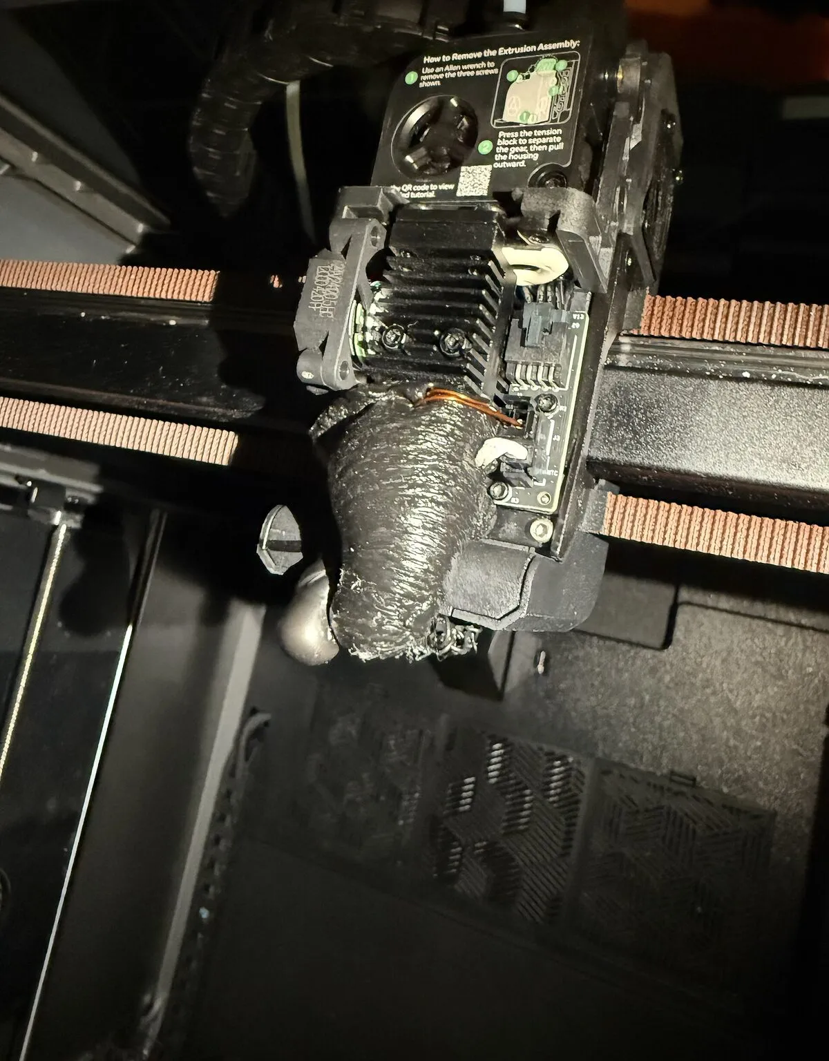 A printer hotend encased in a blob of grey plastic after a failed print