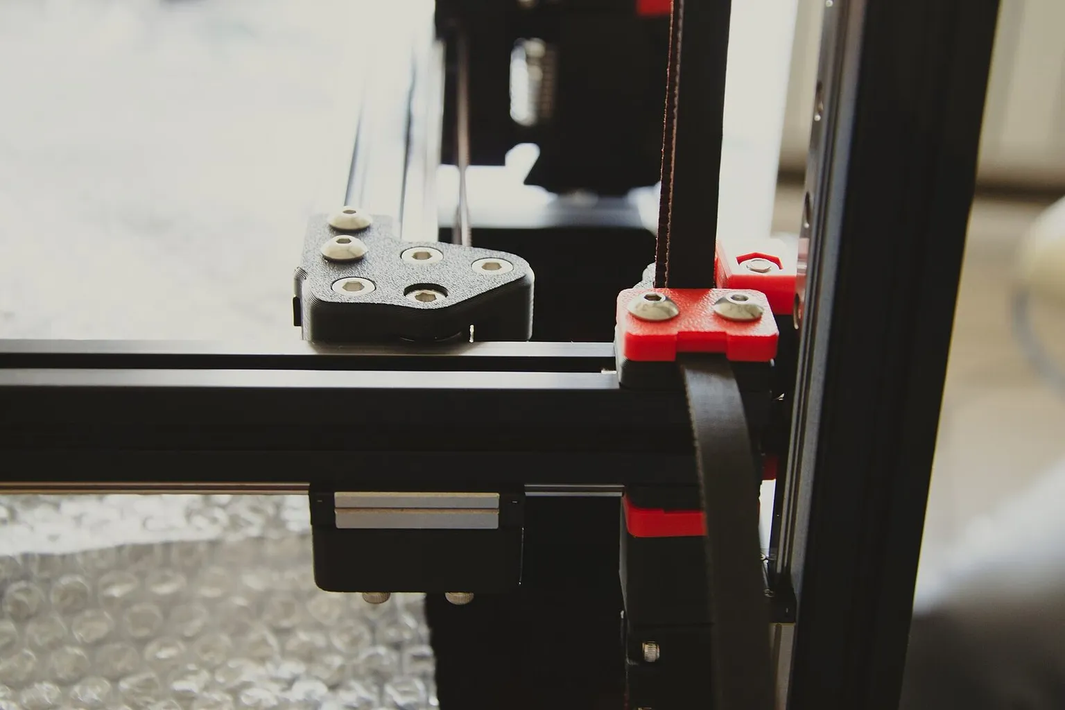 A corner of a Voron frame with an orange printed part on the aluminium extrusion