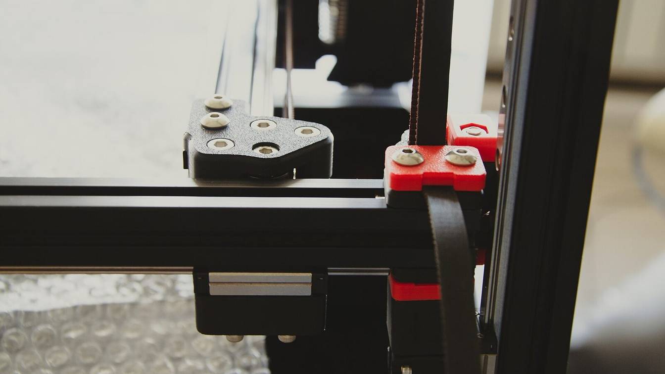 A corner of a Voron frame with an orange printed part on the aluminium extrusion