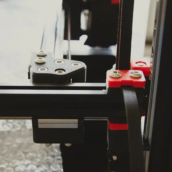 A corner of a Voron frame with an orange printed part on the aluminium extrusion