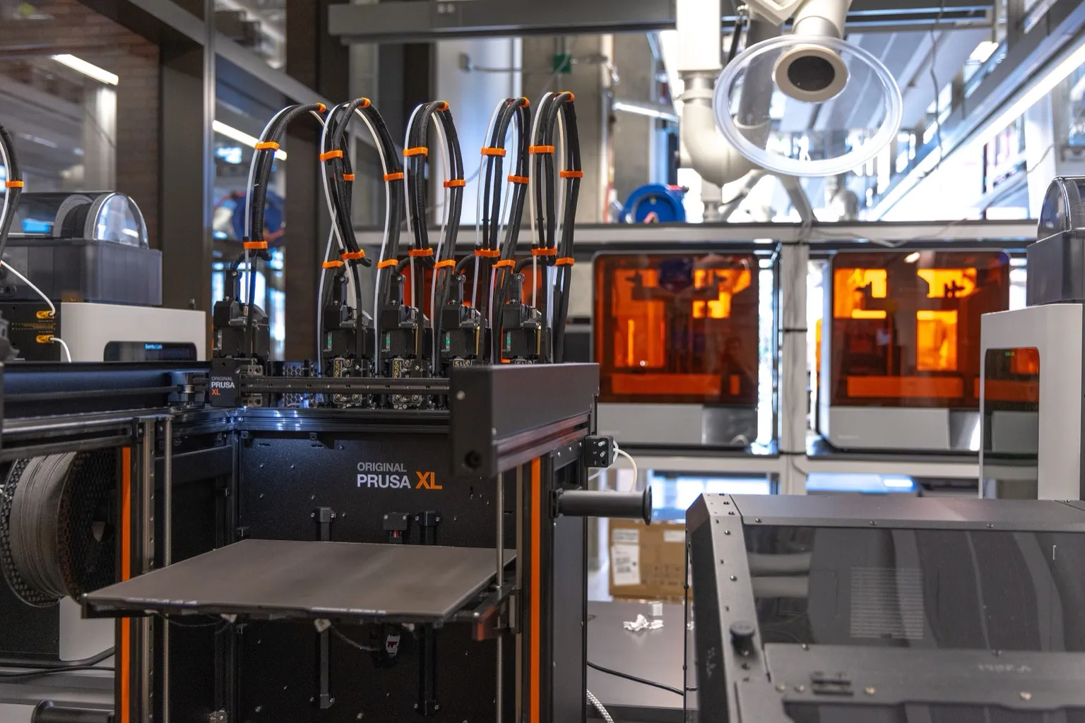 A Prusa XL with five toolheads parked in a row along the top of its frame and its empty carriage at the left, in a university makerspace