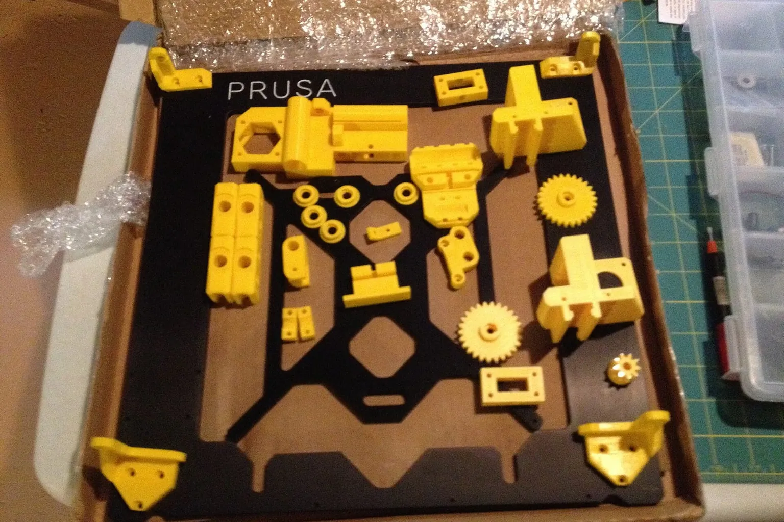 Printed parts and a frame for a Prusa i3 laid out in a box before assembly