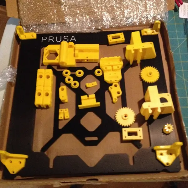 Printed parts and a frame for a Prusa i3 laid out in a box before assembly