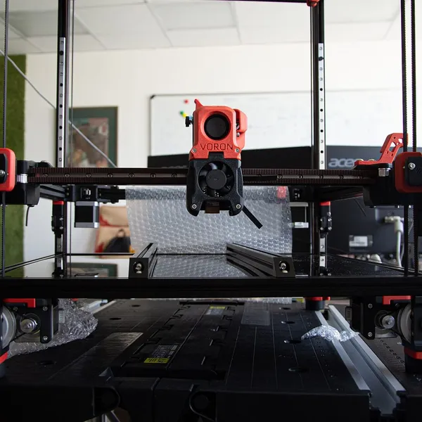 A Voron printer during assembly, its toolhead on the gantry above the bed frame